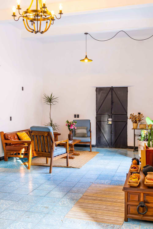 Sala de la Casa Sofi Oaxaca con muebles de madera, asientos azules, araña de bronce y plantas en macetas