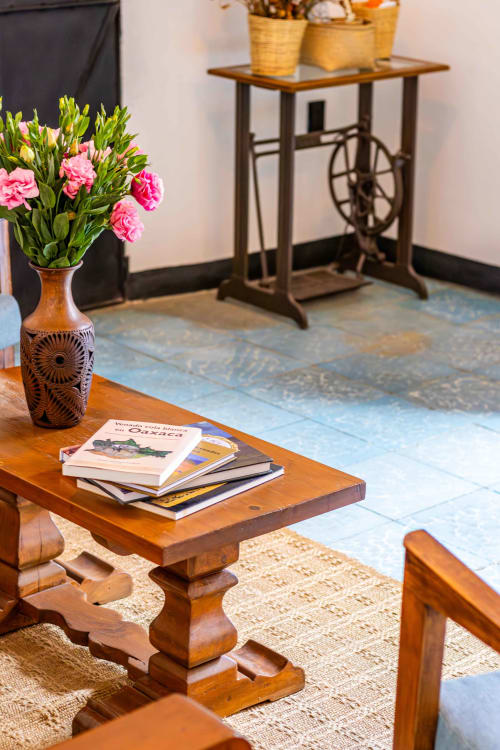 Mesa de madera con flores rosas y libros en la cabaña Casa Sofi Oaxaca, decoración rústica con canastas tejidas