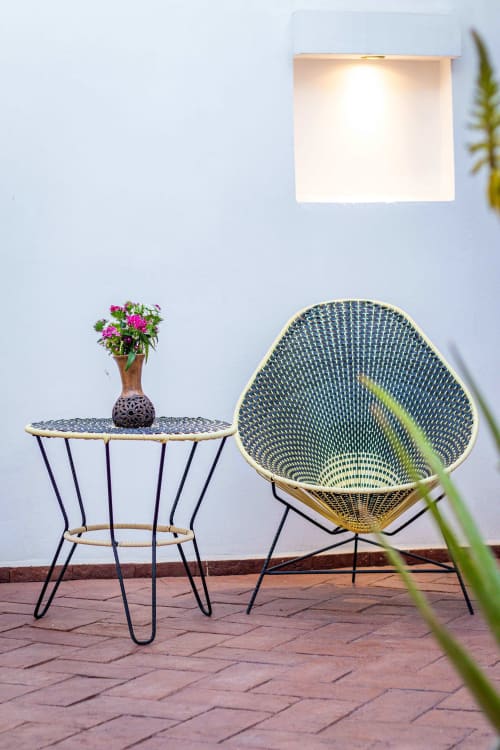 Asiento moderno en la terraza de Casa Sofi Oaxaca con silla tejida, mesita, flores rosas y lámpara de pared blanca