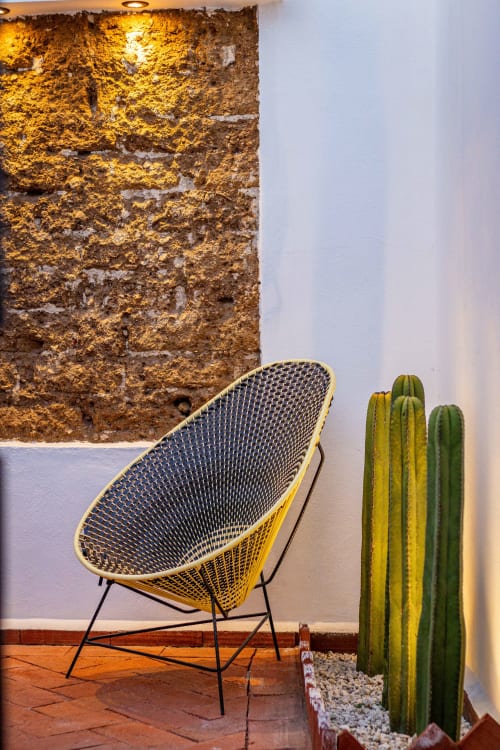 Silla amarilla moderna y cactus alto en patio de piedra rústica de la casita Casa Sofi Oaxaca con muros encalados