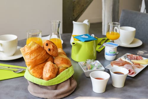 Table de petit-déjeuner de l'Hôtel De La Bonnheure avec viennoiseries, jus, café et charcuterie à Bracieux