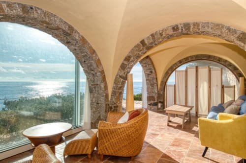 Terrasse côtière avec arches en pierre, sièges en osier et vue sur la Méditerranée à Finques Garcia Enrich, Palafrugell