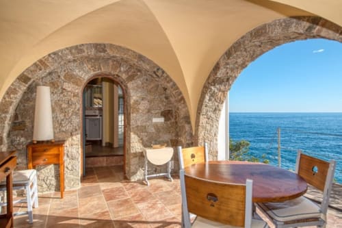 Terrasse voûtée en pierre avec mobilier en bois vue sur la Méditerranée à Finques Garcia Enrich, Palafrugell