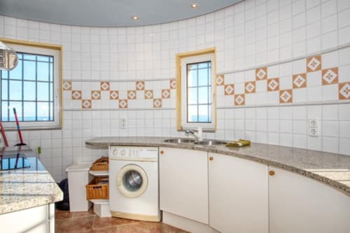 Buanderie moderne aux Finques Garcia Enrich, Palafrugell avec armoires blanches, lave-linge et carrelage décoratif