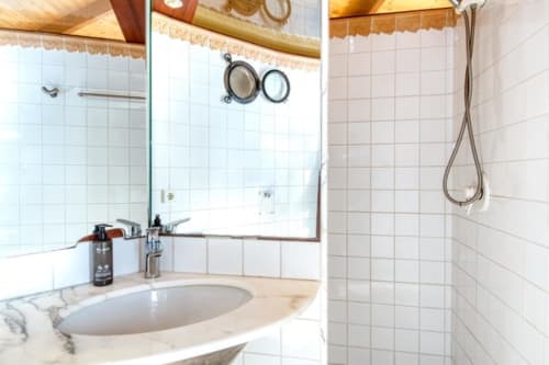 Salle de bain à Finques Garcia Enrich avec lavabo en marbre, grand miroir et douche à Palafrugell, Espagne.