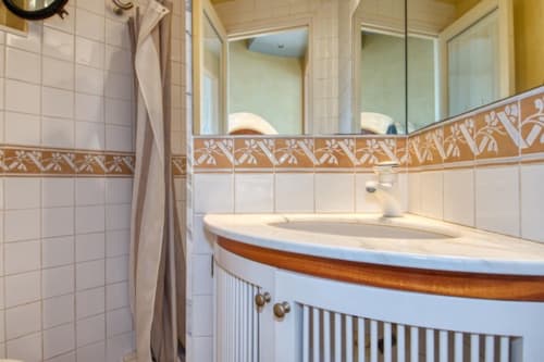 Salle de bain moderne avec vanité courbe, double lavabo, frise carrelage décorative et grand miroir à l'hôtel Finques Garcia Enrich