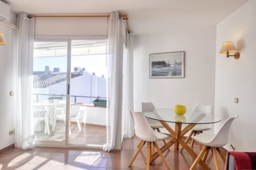 Menjador modern amb taula de vidre, cadires de fusta i accés a la terrassa a Finques Garcia Enrich, Palafrugell