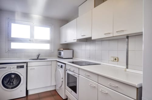 Cuina blanca moderna amb rentadora, forn i microones a l'hotel Finques Garcia Enrich a Palafrugell