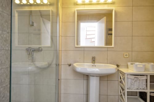 Bany modern a Finques Garcia Enrich a Palafrugell amb lavabo de pedestal, dutxa de vidre i mirall il·luminat
