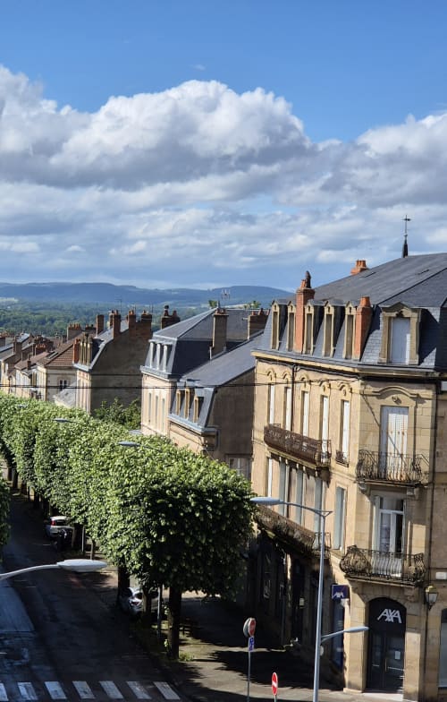 Uitzicht op Autun vanaf appartement Moulin Renaudiots met historische stenen gebouwen en rollende heuvels onder blauwe hemel