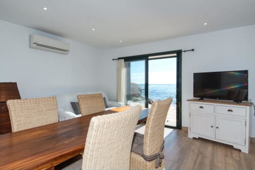 Menjador modern amb vistes a l'oceà a Finques Garcia Enrich, Palafrugell, taula de fusta i cadires de vímet