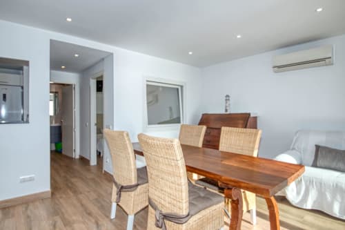 Menjador modern amb taula de fusta i cadires de vime a Finques Garcia Enrich, Palafrugell