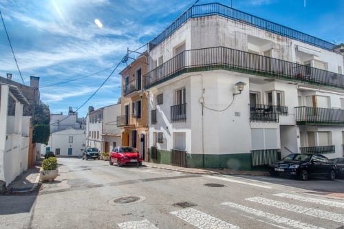 Palafrugell town square with colorful buildings and parked cars under blue sky