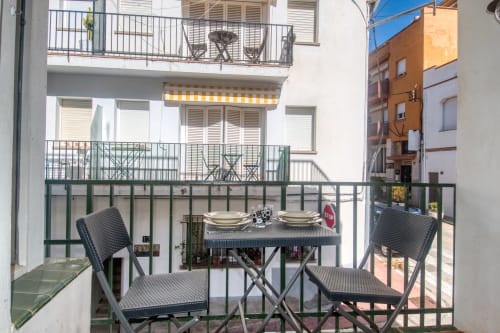 Small apartment balcony with dining table and chairs overlooking Palafrugell street, Finques Garcia Enrich hotel