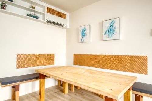 Bright dining area at Finques Garcia Enrich, Palafrugell with wooden table, bench seating, blue wall art and modern shelving.