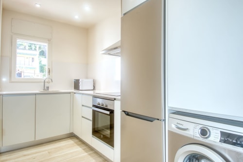 Modern kitchen at Finques Garcia Enrich, Palafrugell with white cabinets, stainless steel appliances and natural light