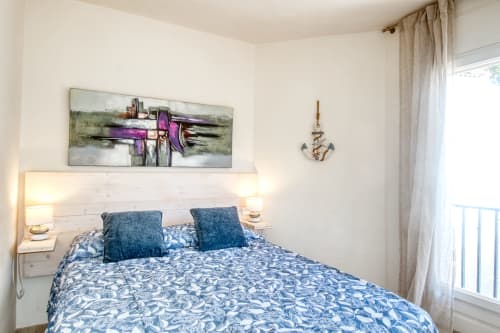 Bright bedroom at Finques Garcia Enrich in Palafrugell with blue patterned bedding, wooden headboard, and coastal decor