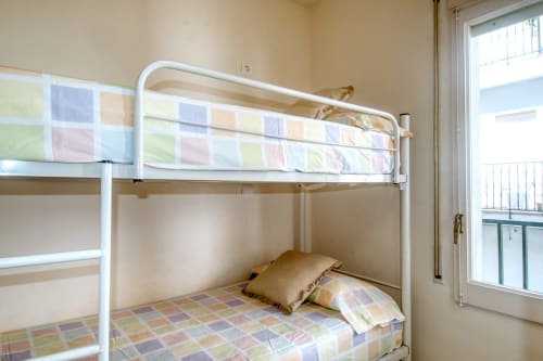 White metal bunk beds with colorful bedding in a bright room at Finques Garcia Enrich hotel in Palafrugell