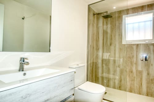 Modern bathroom at Finques Garcia Enrich in Palafrugell with walk-in shower, vanity sink, and wood-grain tile accents