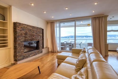 Lujoso salón con vistas al mar, chimenea de ladrillo y asientos en cuero beige en Finques Garcia Enrich, Palafrugell