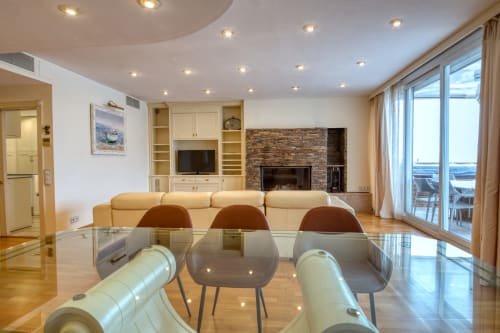 Lujoso salón en Finques Garcia Enrich, Palafrugell con sofá color crema, chimenea y vistas al mar