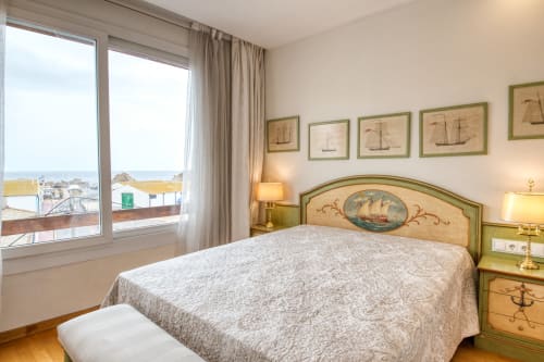 Habitación costera en Finques Garcia Enrich con vistas al mar, decoración náutica y cuadros de barcos tradicionales en Palafrugell