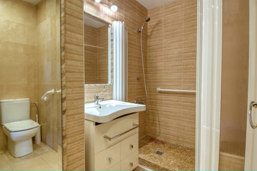Baño moderno con ducha abierta, lavabo y paredes alicatadas en madera en el hotel Finques Garcia Enrich de Palafrugell