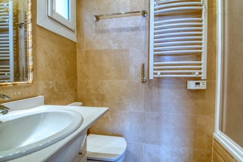 Baño moderno del hotel Finques Garcia Enrich en Palafrugell con lavabo blanco, inodoro, toallero calefactor y ducha alicatada
