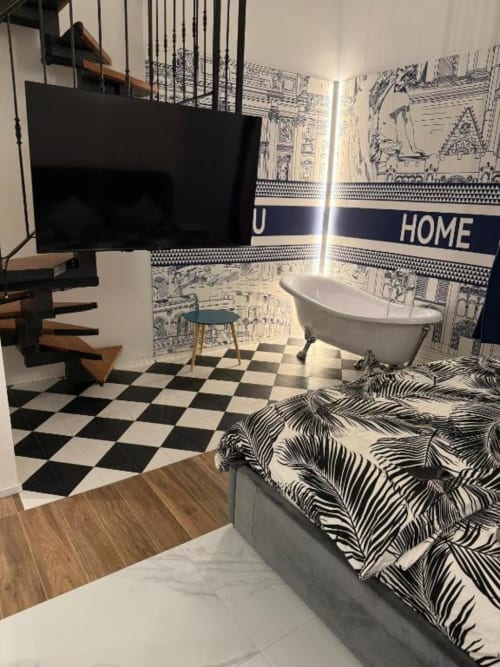 Camera da letto in soppalco St Mary Major a Roma con letto, vasca, pavimento a scacchi bianconeri e TV