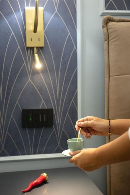 Ospite versa acqua calda dal bollitore elettrico nella tazza nella suite Azure di Pignasecca Domus, camera moderna dell'hotel Napoli