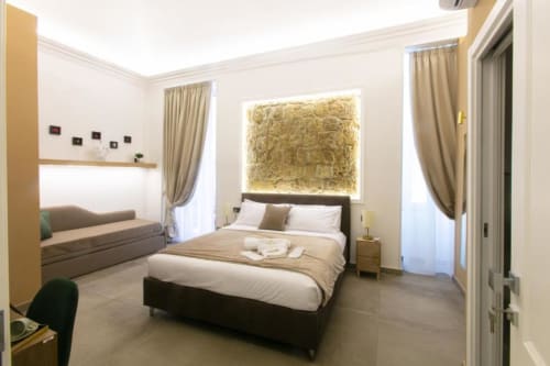 Camera Modern Stone Suite presso Pignasecca Domus a Napoli con letto nero, divano, opere in foglia d'oro e vista sulla città
