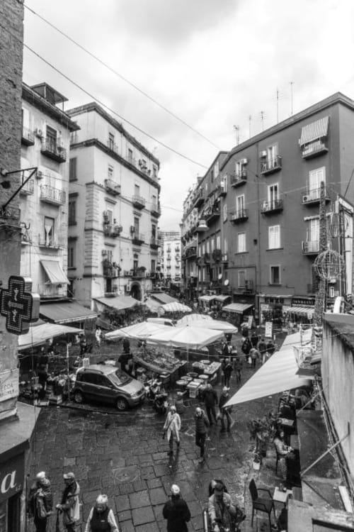 Piazza Pignasecca a Napoli: edifici colorati, tavolini all'aperto e vivace atmosfera cittadina