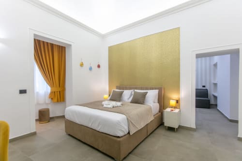 Suite Oro di Pignasecca Domus, Napoli - camera moderna con parete accent dorata, letto matrimoniale, tende gialle e vista sulla città
