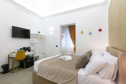 Camera da letto moderna a Pignasecca Domus a Napoli con letto, TV, scrivania e lampade a sospensione colorate