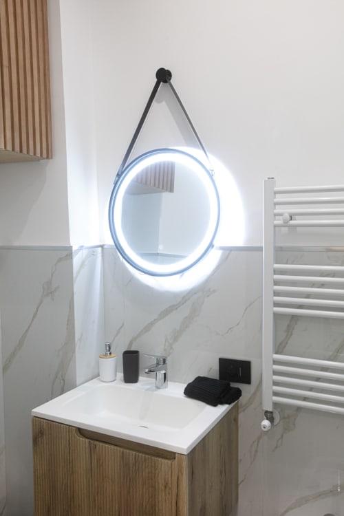 Lavabo moderno con specchio circolare illuminato nella Gold Suite di Pignasecca Domus a Napoli