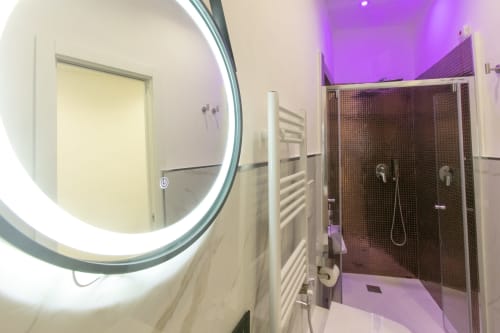Bagno moderno della Gold Suite presso Pignasecca Domus Naples BnB con specchio rotondo illuminato, cabina doccia e scaldasalviette