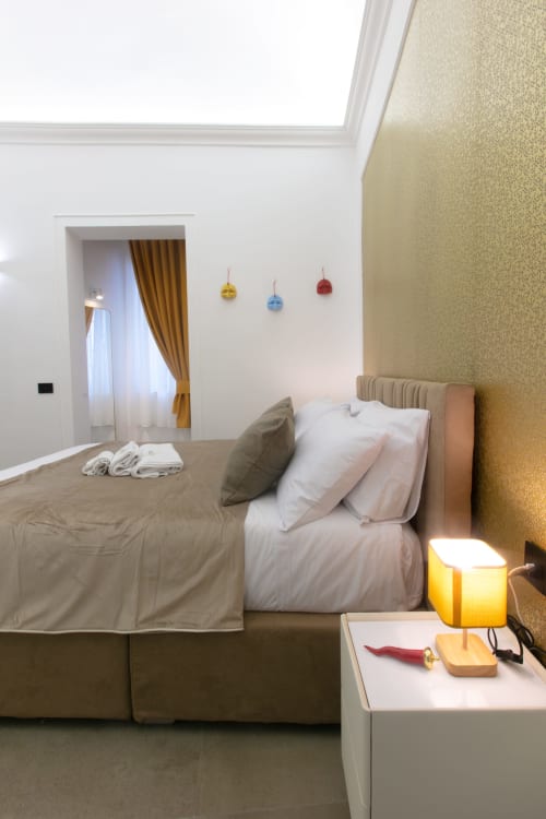 Camera della suite Modern Gold presso il Pignasecca Domus di Napoli con letto, lampada da scrivania e ornamenti colorati