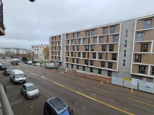 Construction d'immeuble moderne à Vandoeuvre-les-Nancy avec vue sur la ville, voitures garées dans la rue