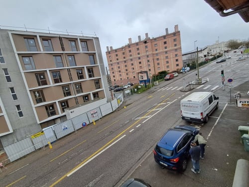 Vue de la rue du NancyRoom BnB à Vandoeuvre-les-Nancy avec bâtiments modernes et voitures garées
