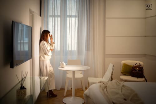 Woman in beige suit at Stella CasaBono Junior Suite in Sulmona, modern minimalist room with TV and window