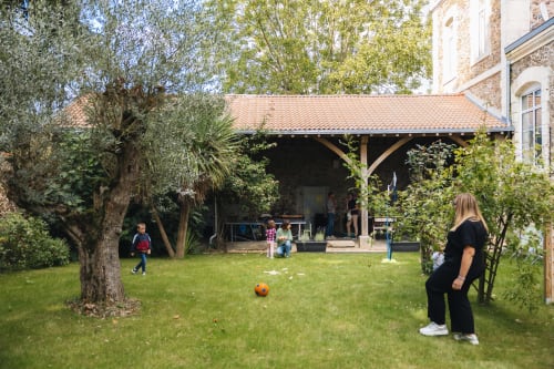 Cour de jardinage à la Maison D'olivier avec pelouse, pergola en bois et clients jouant au ballon