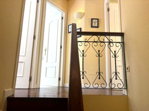 Elegante escalera con barandilla de hierro negro ornamentado en dúplex Holibai, Baiona, hacia terraza con vistas al mar