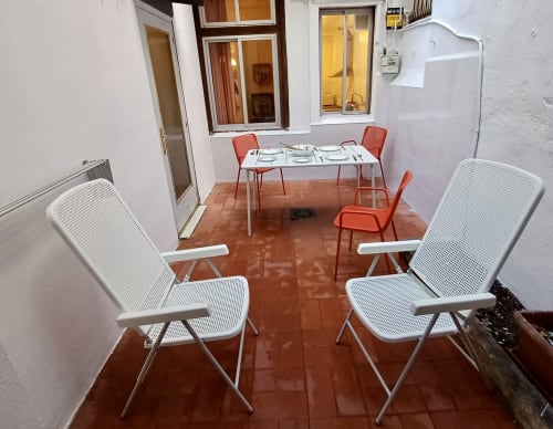 Cozy Barcelona apartment patio with white chairs, dining table, and terracotta tiles at Mira Barna