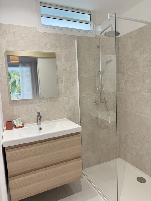 Salle de bain moderne au Domaine de la Glacière avec douche à l'italienne, lavabo et lumière naturelle par la fenêtre
