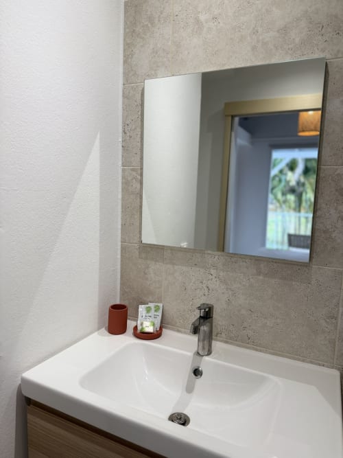 Lavabo moderne de l'hôtel Domaine de la Glacière à Petit Bourg avec miroir et murs en carrelage beige