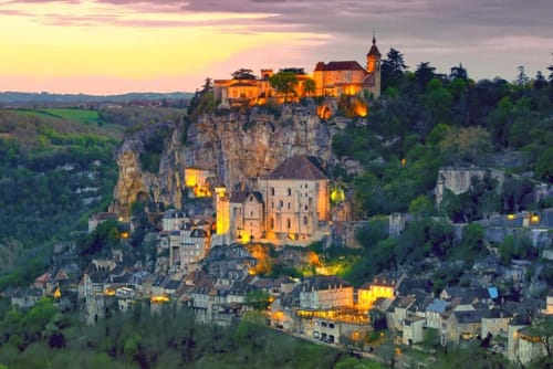 Medieval castle illuminated at dusk overlooking Dordogne village, near Domaine De Campagnac in Carsac-Aillac