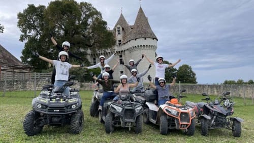 Group on ATVs celebrating at Domaine De Campagnac with medieval castle backdrop in Carsac-Aillac