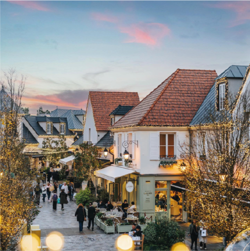 Charmant village de style toscan au resort Disneyland Paris avec restaurants illuminés, arbres décorés et visiteurs profitant du lieu