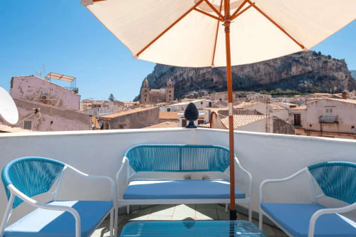 Terrazza sul tetto di CefalHome con sedie blu, ombrellone e vista sulla cattedrale di Palermo in Sicilia