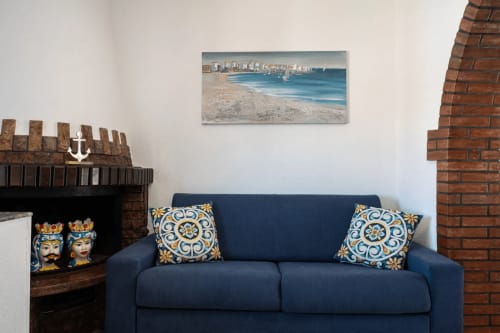 CefalHome Roma: Soggiorno a tema costiero con divano blu navy, cuscini blu patterned, camino e opere d'arte marina